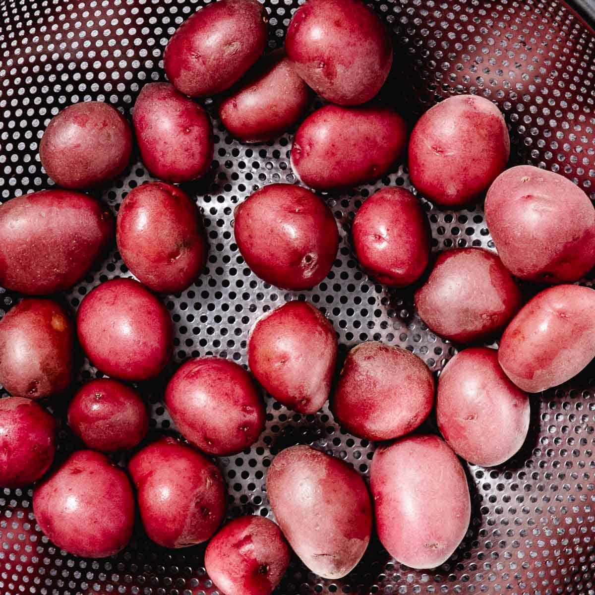 rinsing red potatoes in a colander.