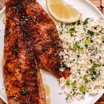 Baked red snapper fillets with lemon butter, rice, scallions, and lemon.