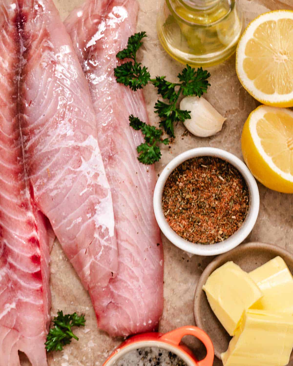 Raw red snapper fillets with lemon, butter, olive oil, garlic, parsley, salt, pepper, and blackened seasoning.