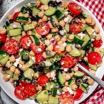 Cold chickpea cucumber feta salad in a bowl with red gingham napkin.