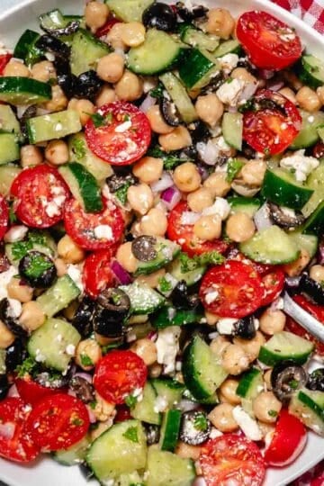 Cold chickpea cucumber feta salad in a bowl with red gingham napkin.