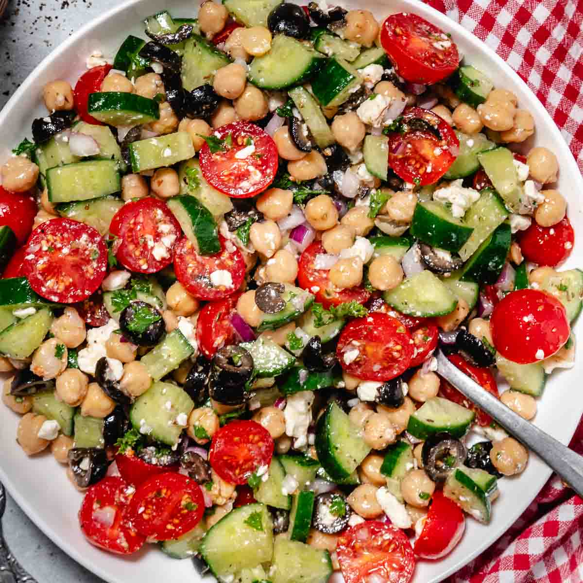 Cold chickpea cucumber feta salad in a bowl with red gingham napkin.