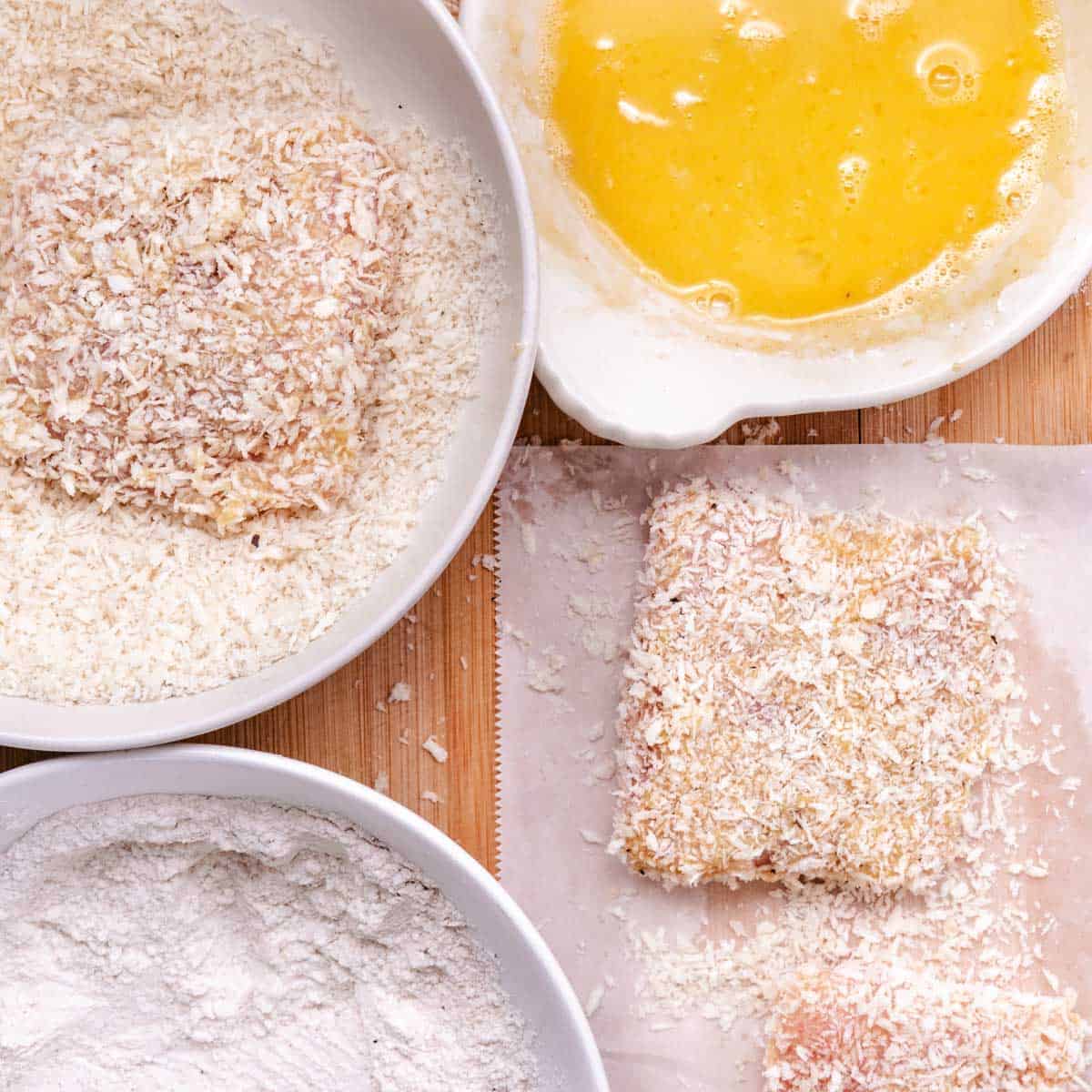 Panko-breaded mahi mahi fillets being coated for frying with flour, egg wash, and breadcrumbs in a breading station.