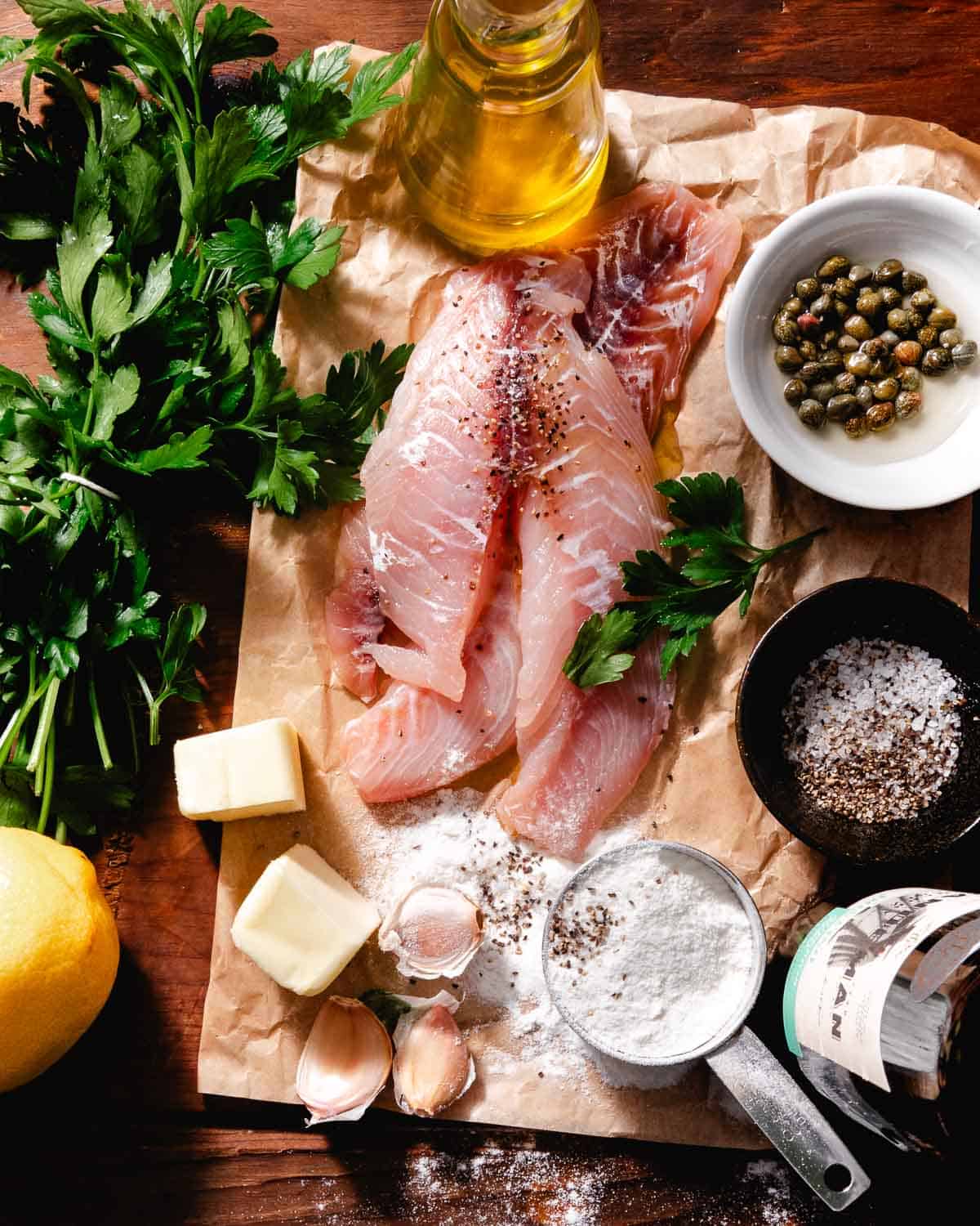 Ingredients for fish picatta including fresh yellowtail, garlic, butter, capers, and lemon.