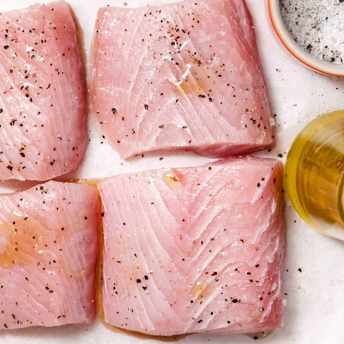 Raw mahi mahi fillets seasoned with salt, black pepper, and oil before frying.