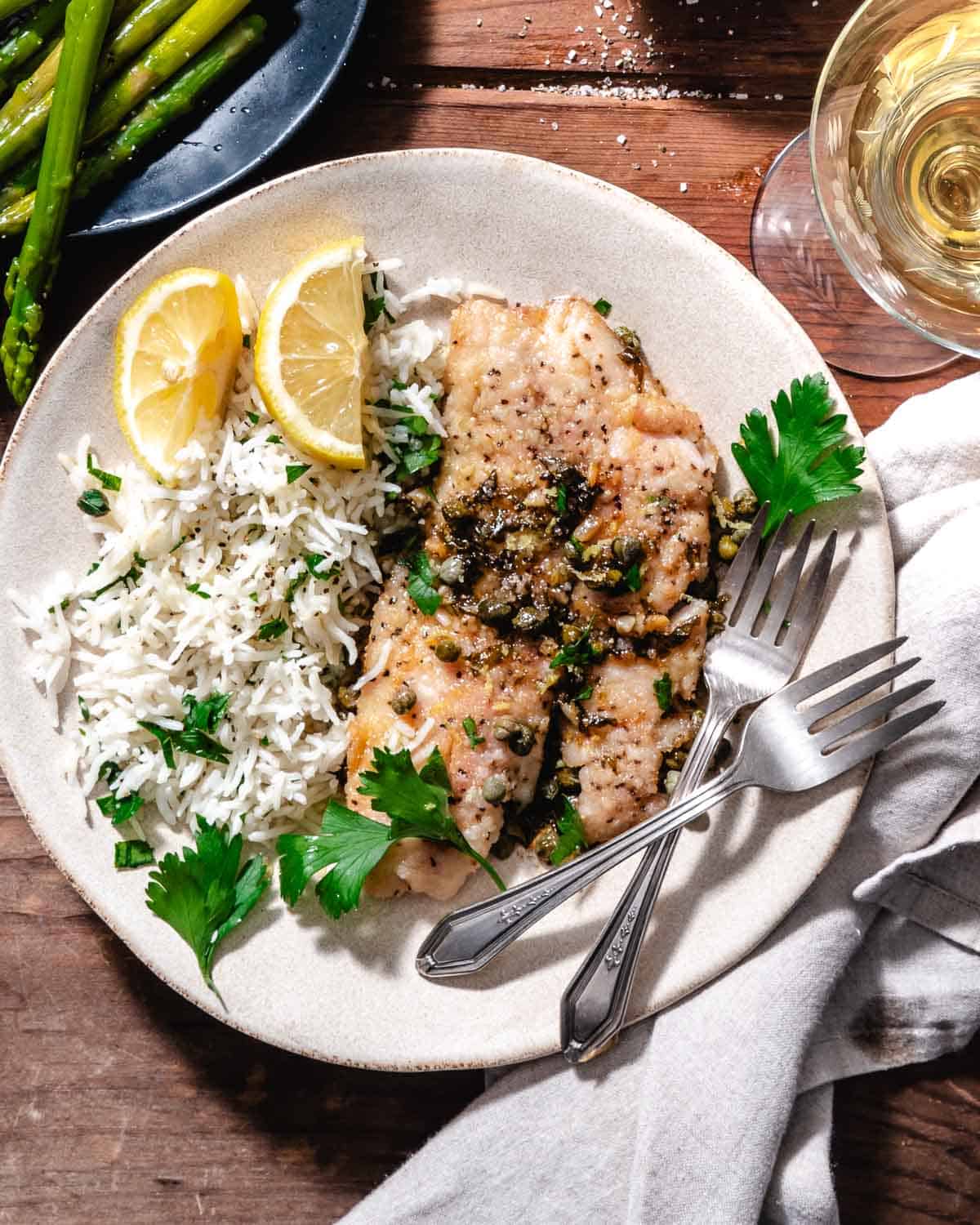 Fish piccata with rice. Lemon wedges, and asparagus.
