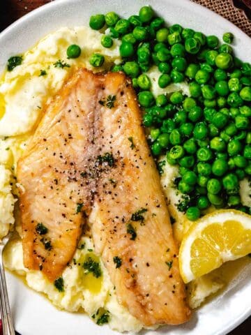 Mashed potatoes and fish with peas.