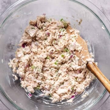 Classic diner-style tuna salad mixed in a glass bowl with a wooden spoon