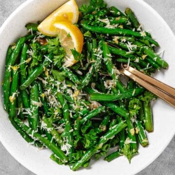 Bowl of garlic green beans with cheese and lemin.