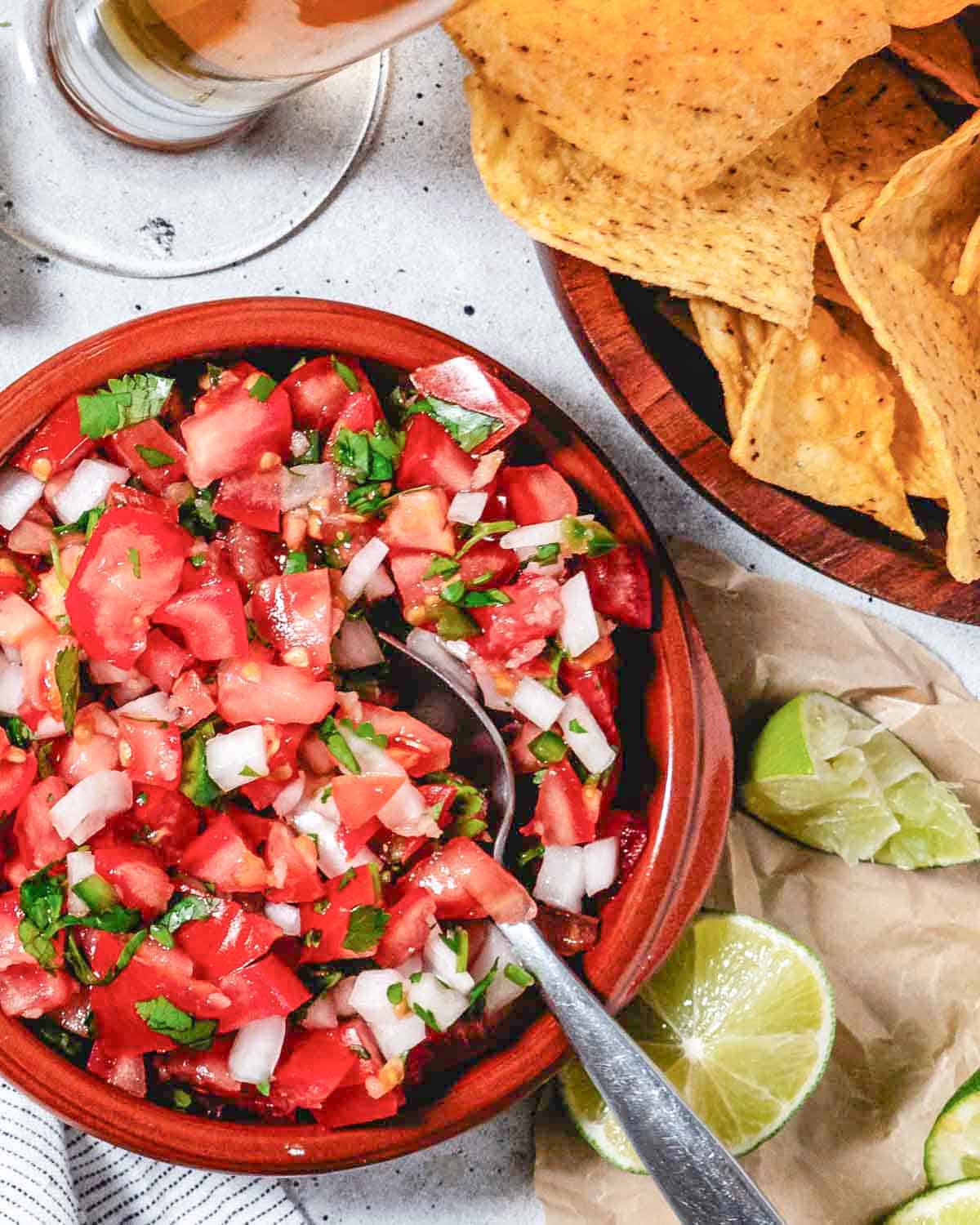 pico de gallo in a bnowl next to tortilla chips with lime