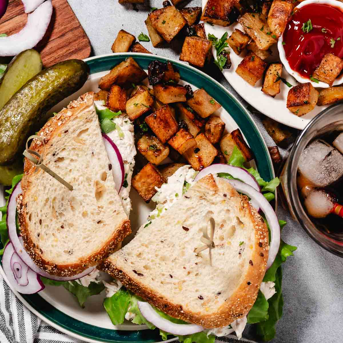 chicken salad on a plate with roasted russet potatoes, ketchup, and pickles