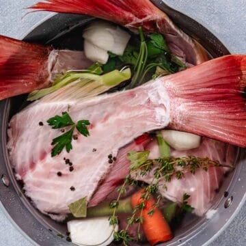 Red snapper bones with vegetables and herbs in a pot for homemade fish stock.