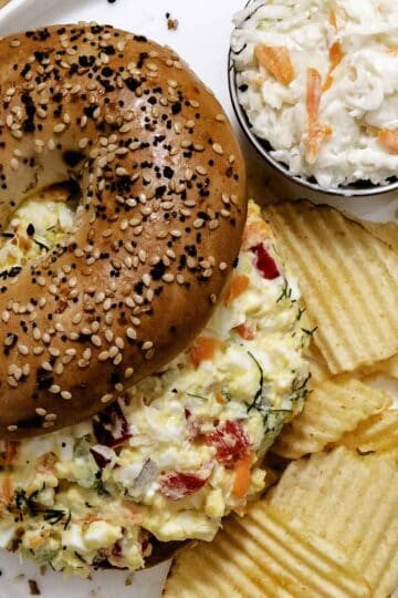 Garden vegetable egg salad with tomato and chips with a side of coleslaw.