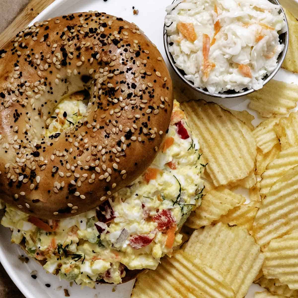 Garden vegetable egg salad with tomato and chips with a side of coleslaw.