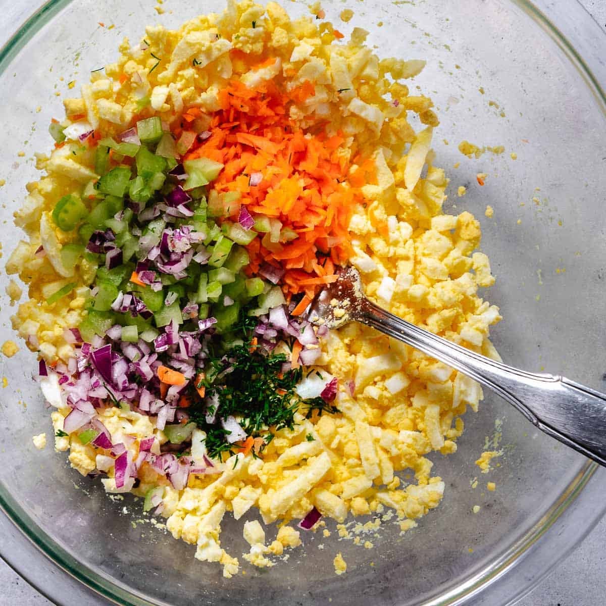 mixing veggie egg salad in a bowl