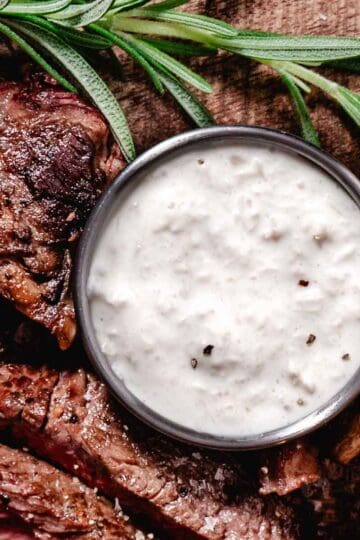 Horseradish sauce for prime rib with sliced steak on a wooden board