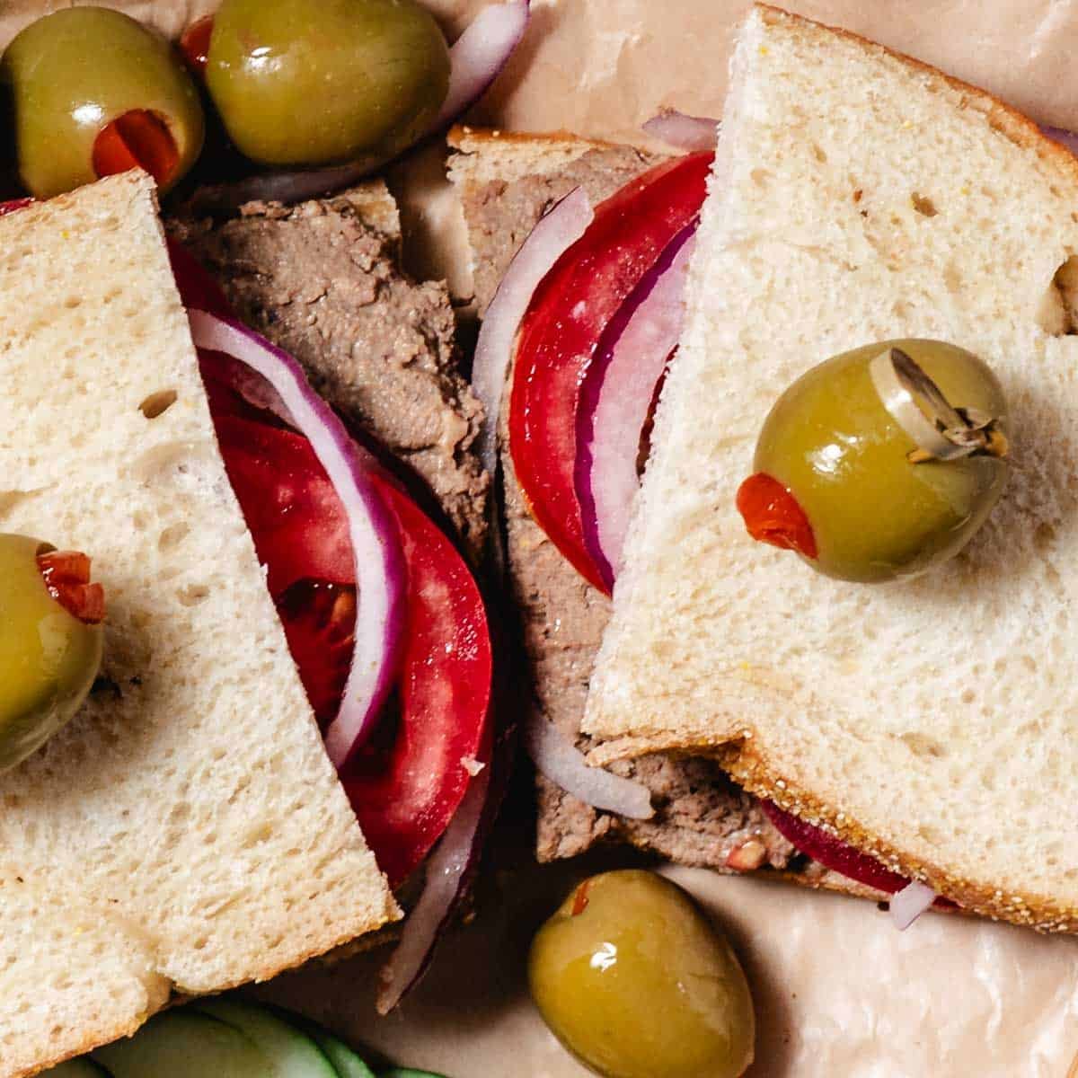 deli style chopped liver spread sandwich with tomatoes and onions.