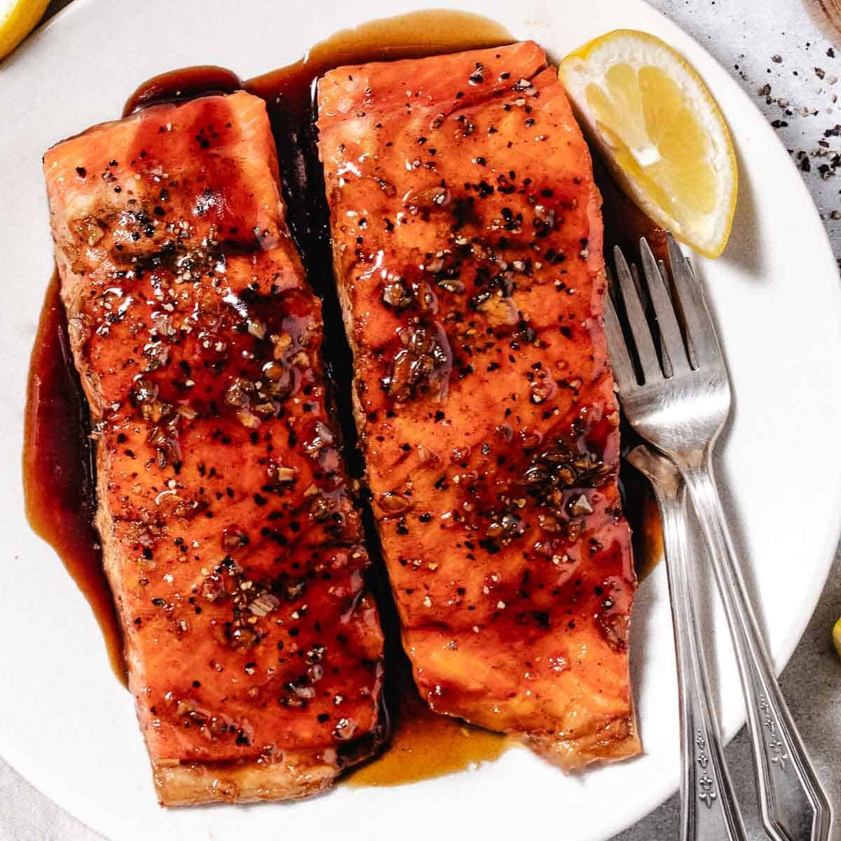 salmon with sweet honey glaze and lemon on a plate.