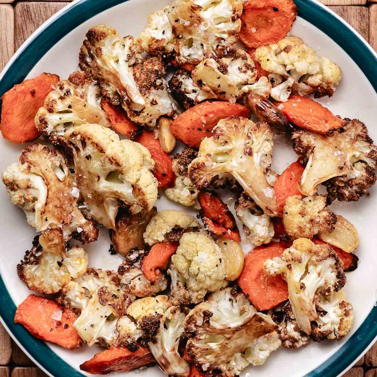 Roasted cauliflower, carrots, and garlic on a plate.
