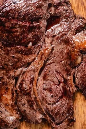 Sliced pan-seared chuck steak on a wooden cutting board.
