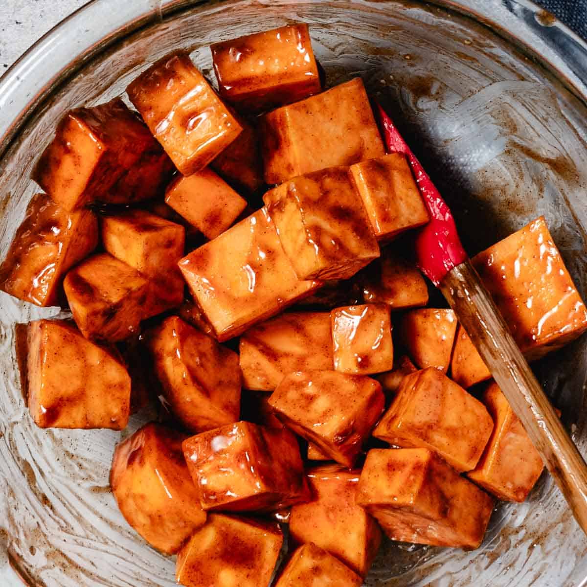 Mixing cinnamon sugar sweet potato cubes in mixing bowl.
