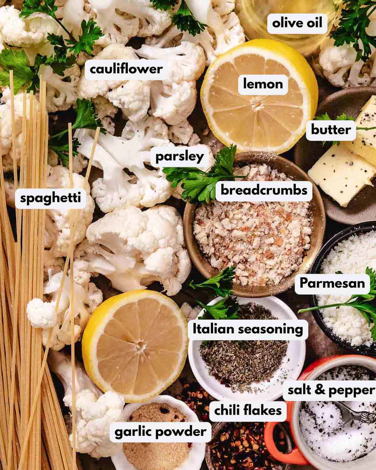 Labeled ingredients for cauliflower pasta with spaghetti, cauliflower, breadcrumbs, Parmesan, butter, olive oil, lemon, parsley, chili flakes, and seasonings.
