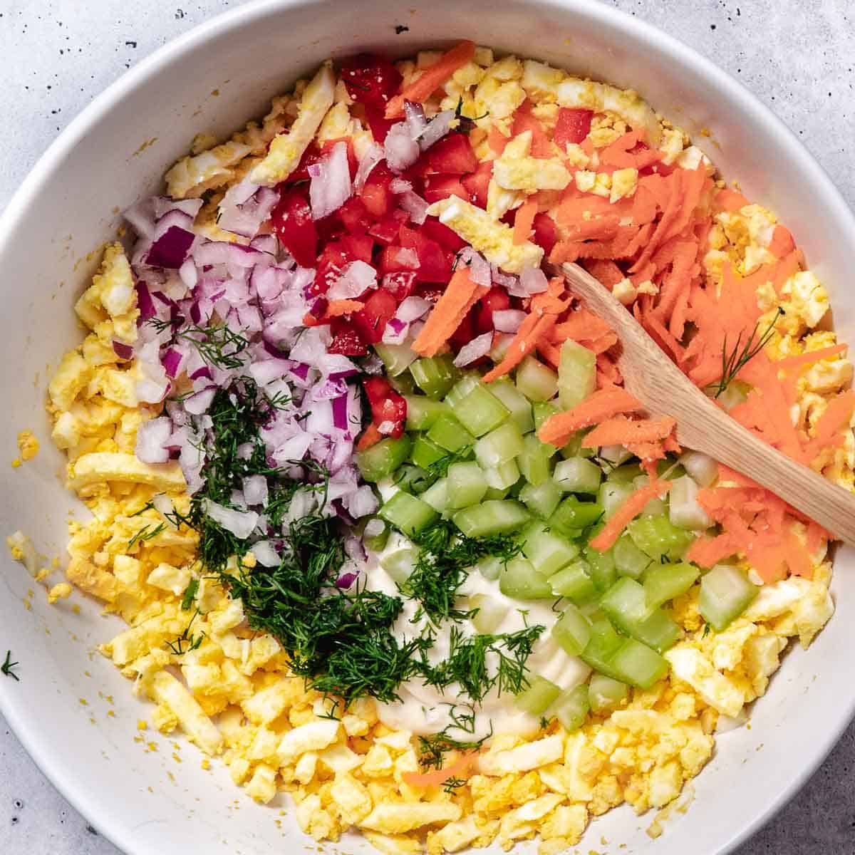 Mixing veggie egg salad in a bowl.