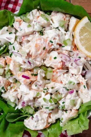 Bowl of cold lobster salad with chunks of lobster, celery, and dressing in a light dressing