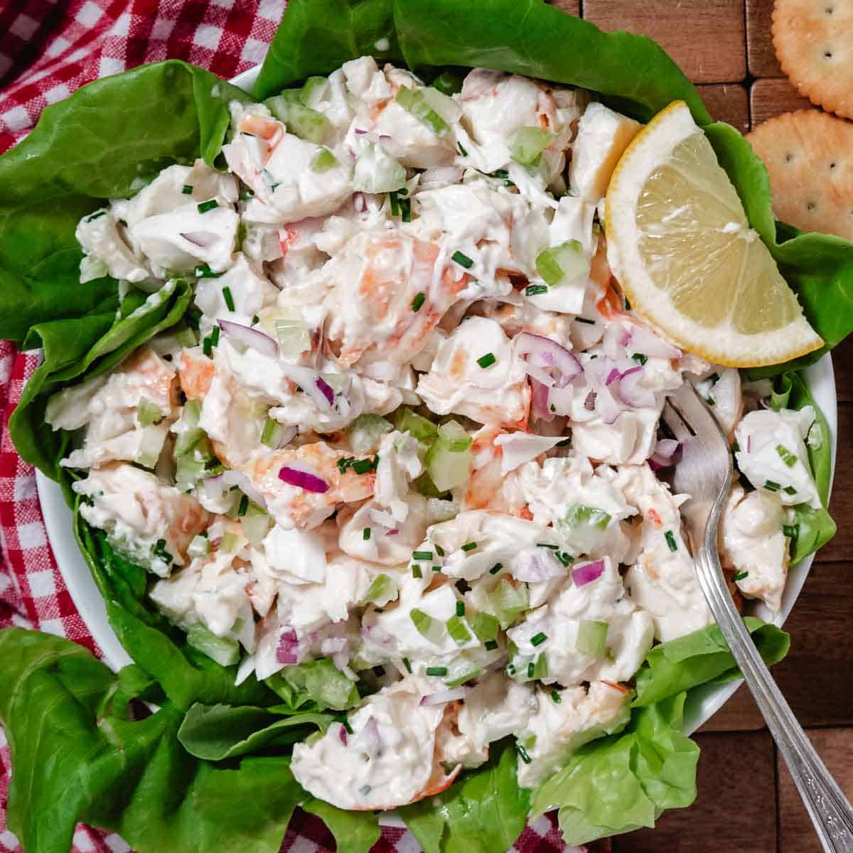 Bowl of cold lobster salad with chunks of lobster, celery, and dressing in a light dressing