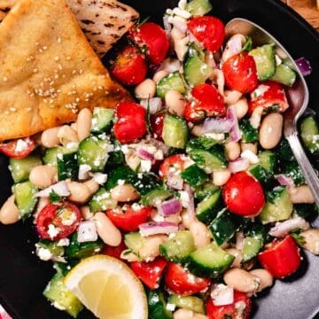 white bean cucumber dill salad with vinaigrette and a lemon wedge