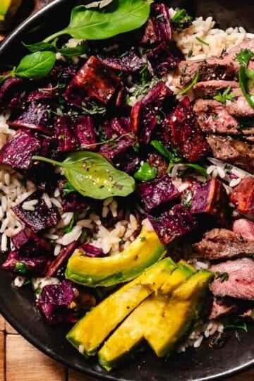 steak and sweet potatoes bowl with avocado slices and basil leaves over rice