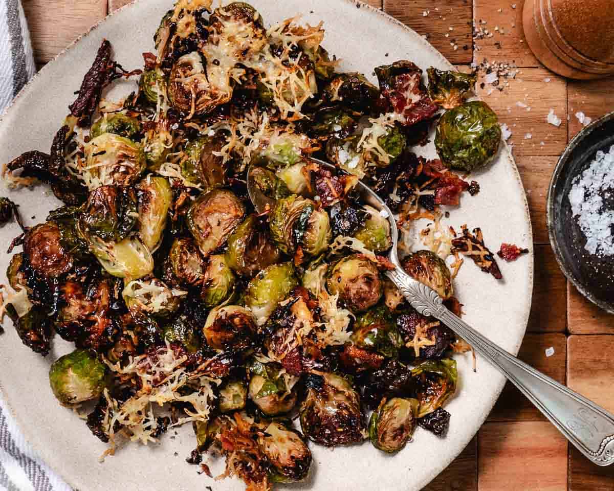 Overhead view of bowl of roasted Brussels sprouts with bacon and cheese, drizzled with balsamic vinegar.