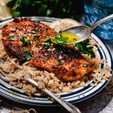 A golden fillet of fish topped with rich lemon garlic butter sauce and fresh herbs.