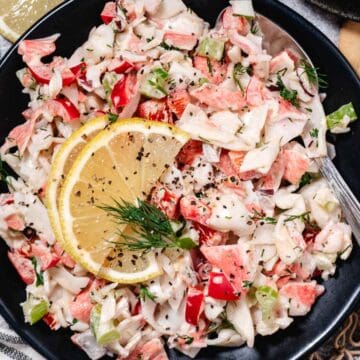 bowl of surimi crab salad with lemon slices.
