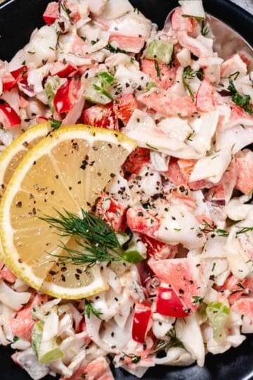 bowl of surimi crab salad with lemon slices.