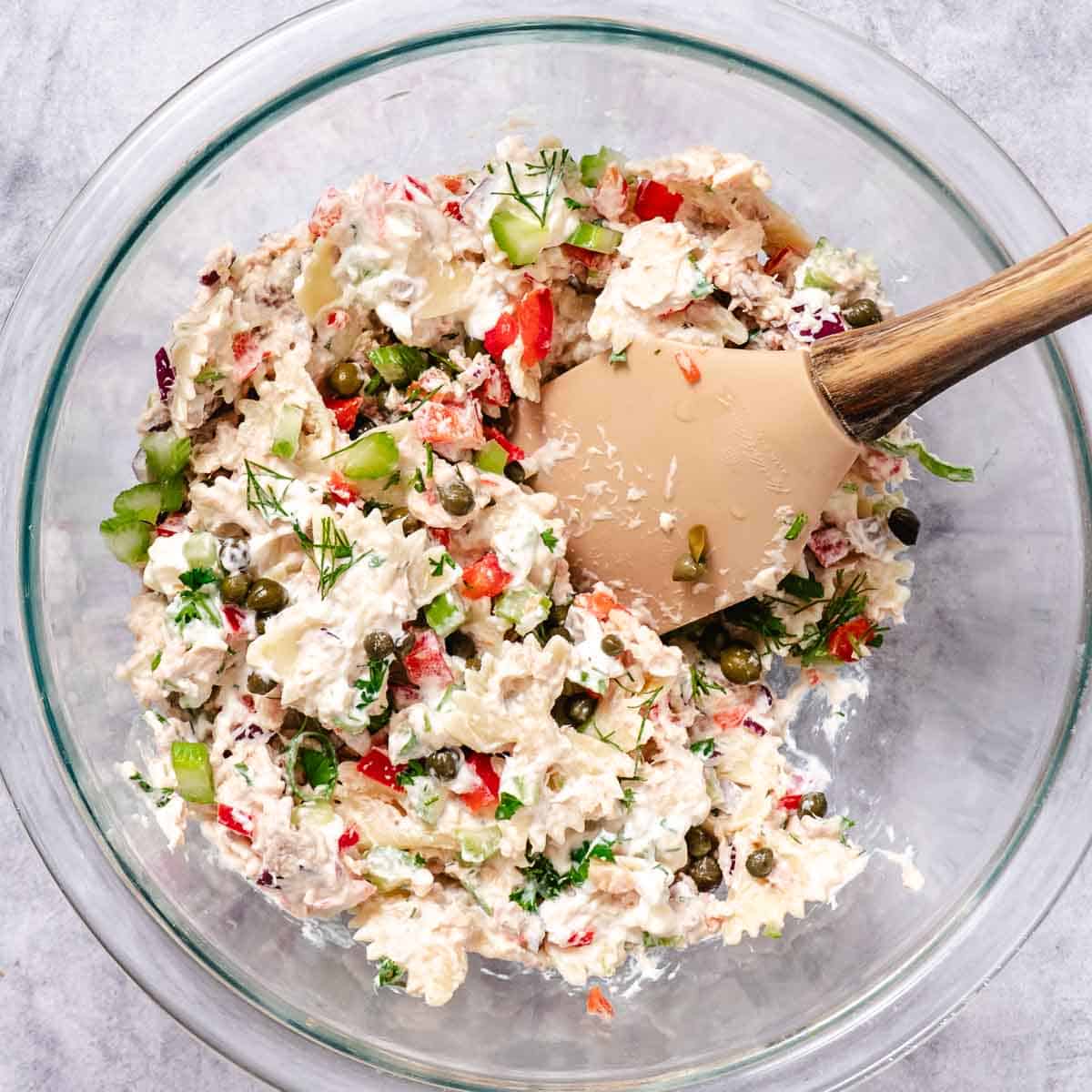 Cominging flaked canned salmon with dressing in mixing bowl.