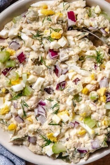 Homemade tuna egg salad with eggs, celery, red onion, dill, and pickles in a shallow bowl