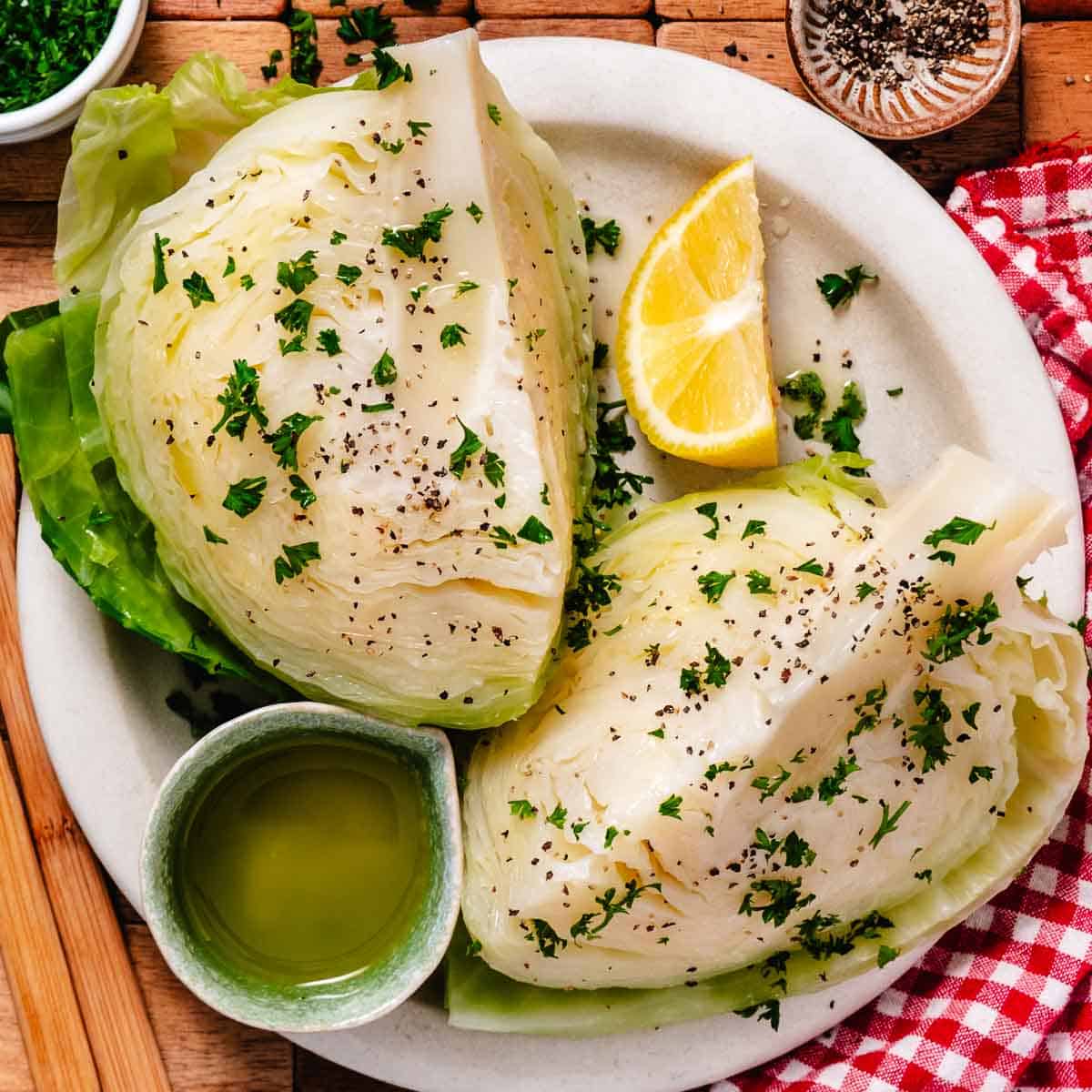 Tender boiled cabbage wedges seasoned with parsley and black pepper, served with olive oil and lemon.