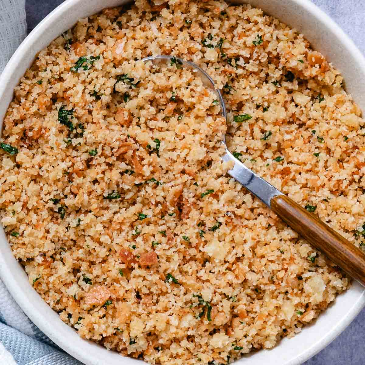 Bowl of buttered bread crumbs with a spoon.