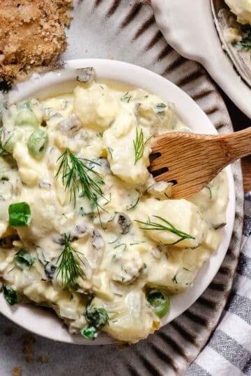 Dill pickle potato salad with eggs and fresh dill served with oven fried chicken.