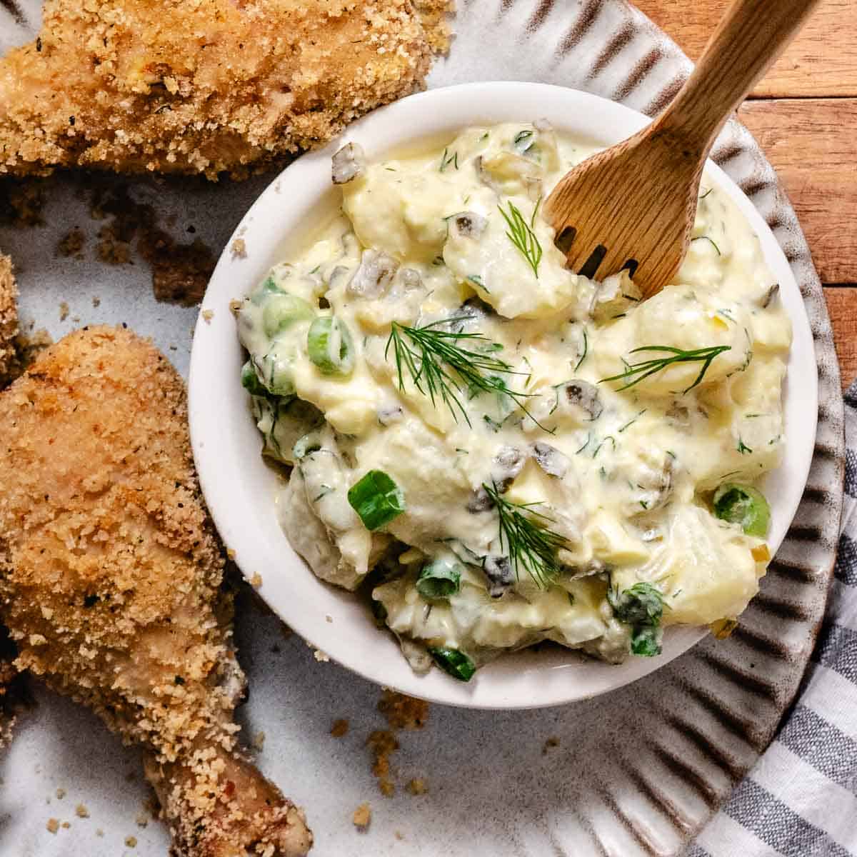 Dill pickle potato salad with eggs and fresh dill served with oven fried chicken.