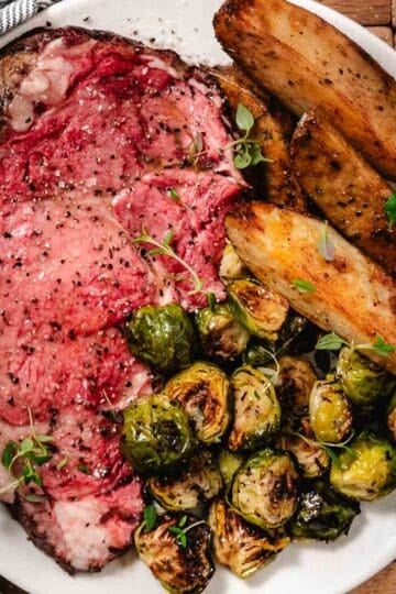 Small standing rib roast cooked to medium rare with Brussels sprouts and potatoes.