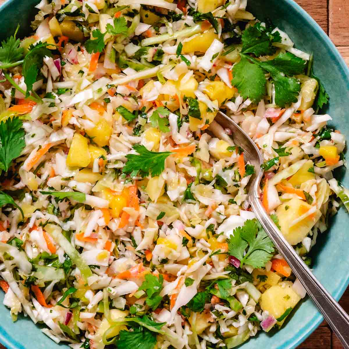 No mayo mango coleslaw with lime, cilantro, and fresh mango in a serving bowl.