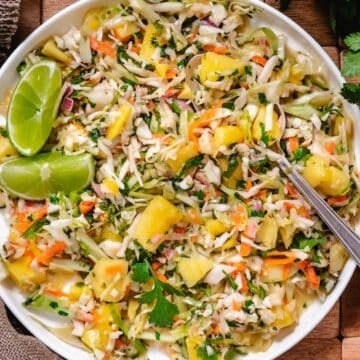 Fresh mango coleslaw with cabbage, mango, cilantro, and lime served in a white bowl.