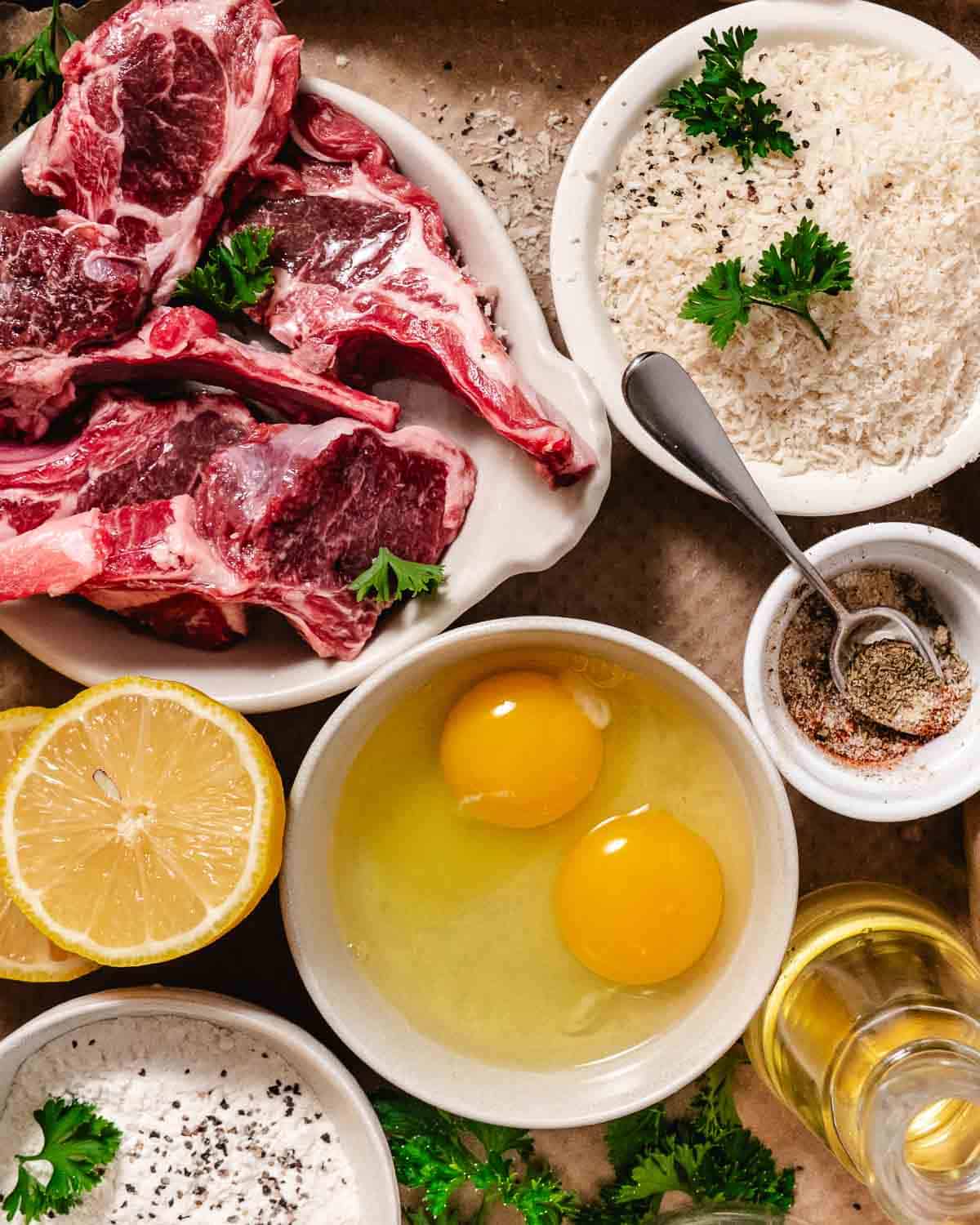 Raw lamb chops with eggs, panko breadcrumbs, lemon, olive oil, and seasonings for breaded lamb chops
