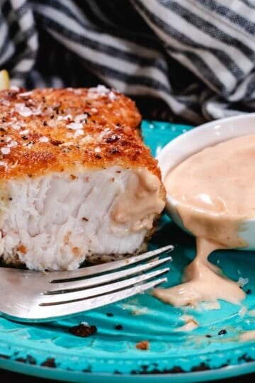 Crispy breaded swordfish steak served with a creamy dipping sauce and lemon wedge on the side.