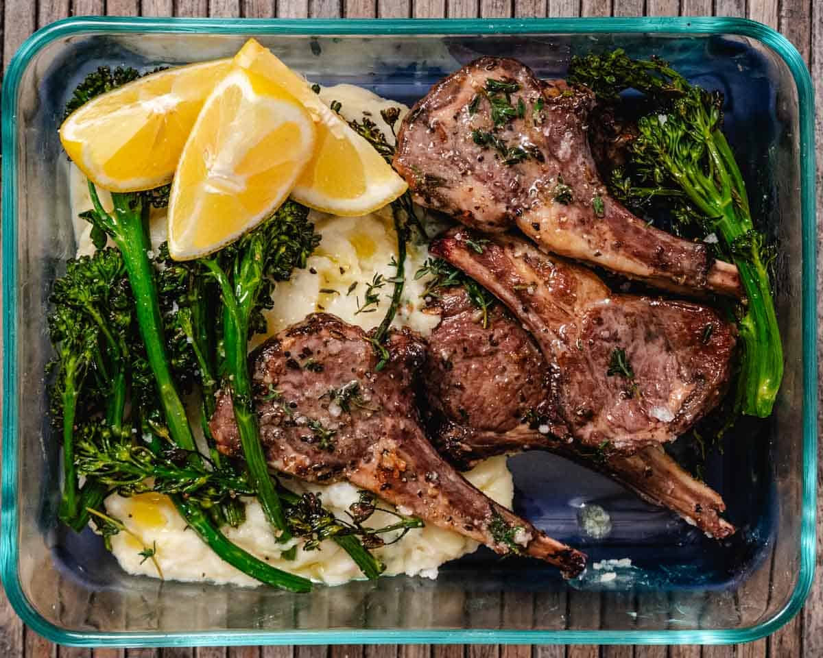 Small lamb chops with mashed potatoes and broccolini with lemon wedges