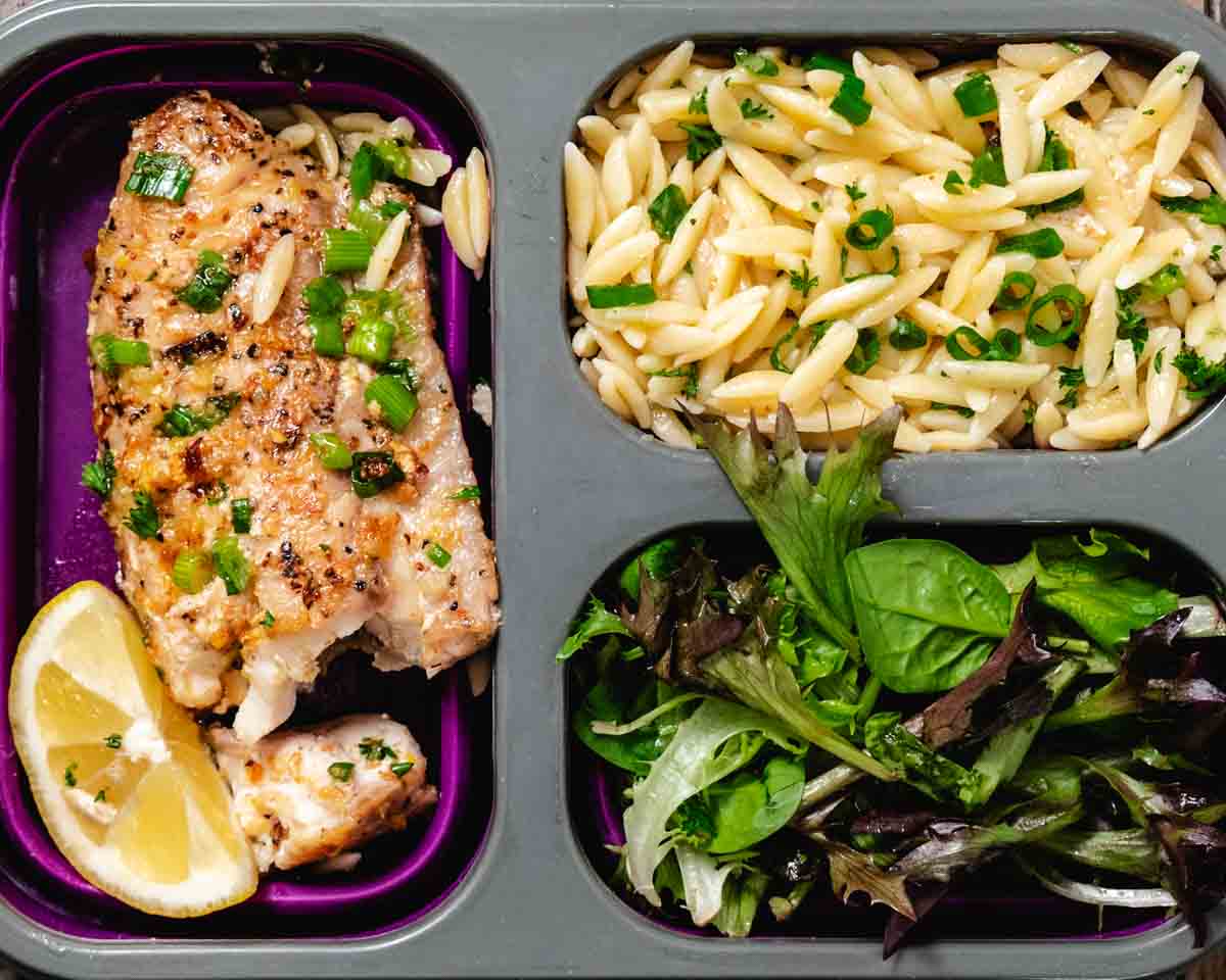 Leftover pan seared tilefish with lemon served in a meal prep container with orzo pasta and mixed greens.