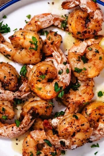 pan seared shrimp on a plate with lemon wedge