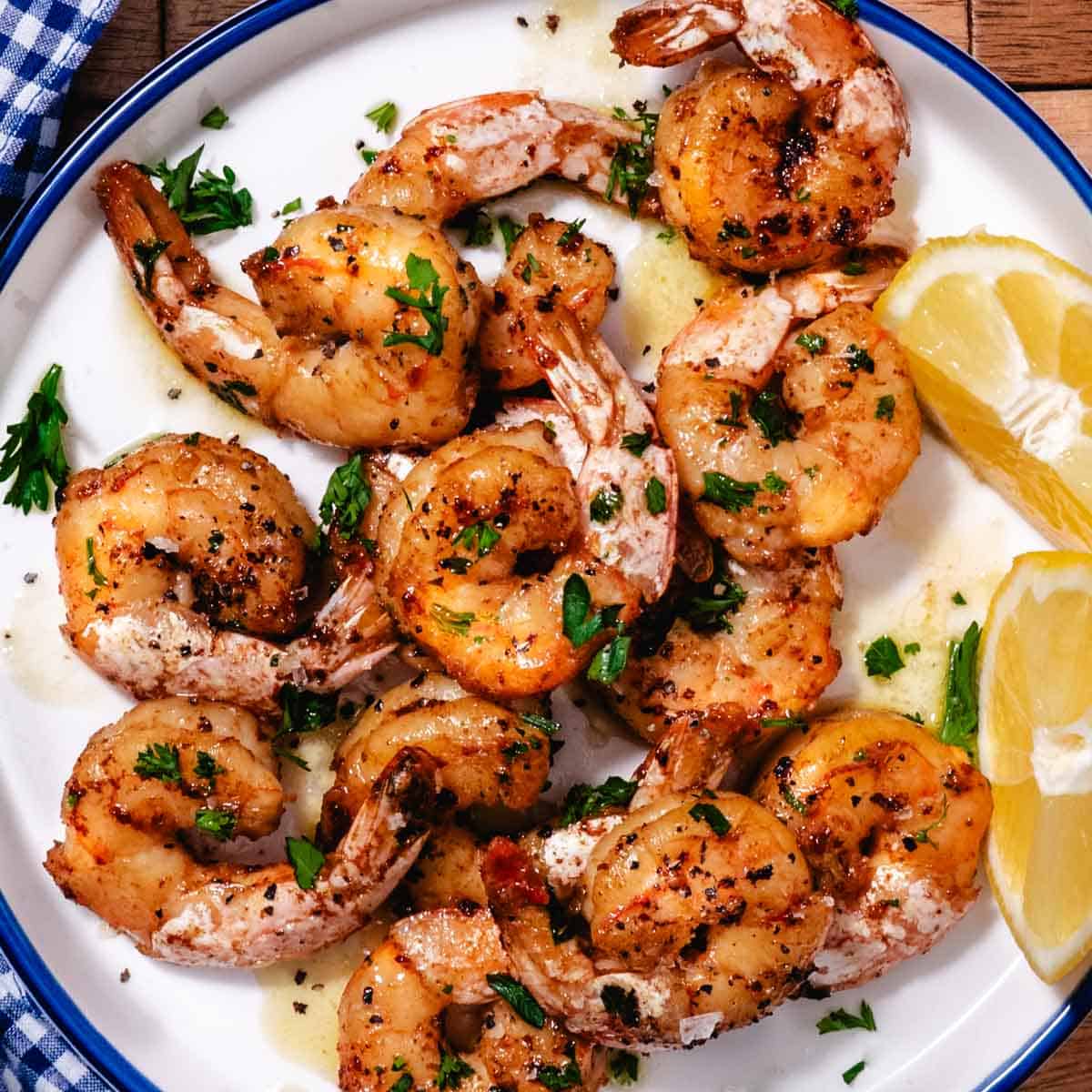 pan seared shrimp on a plate with lemon wedge